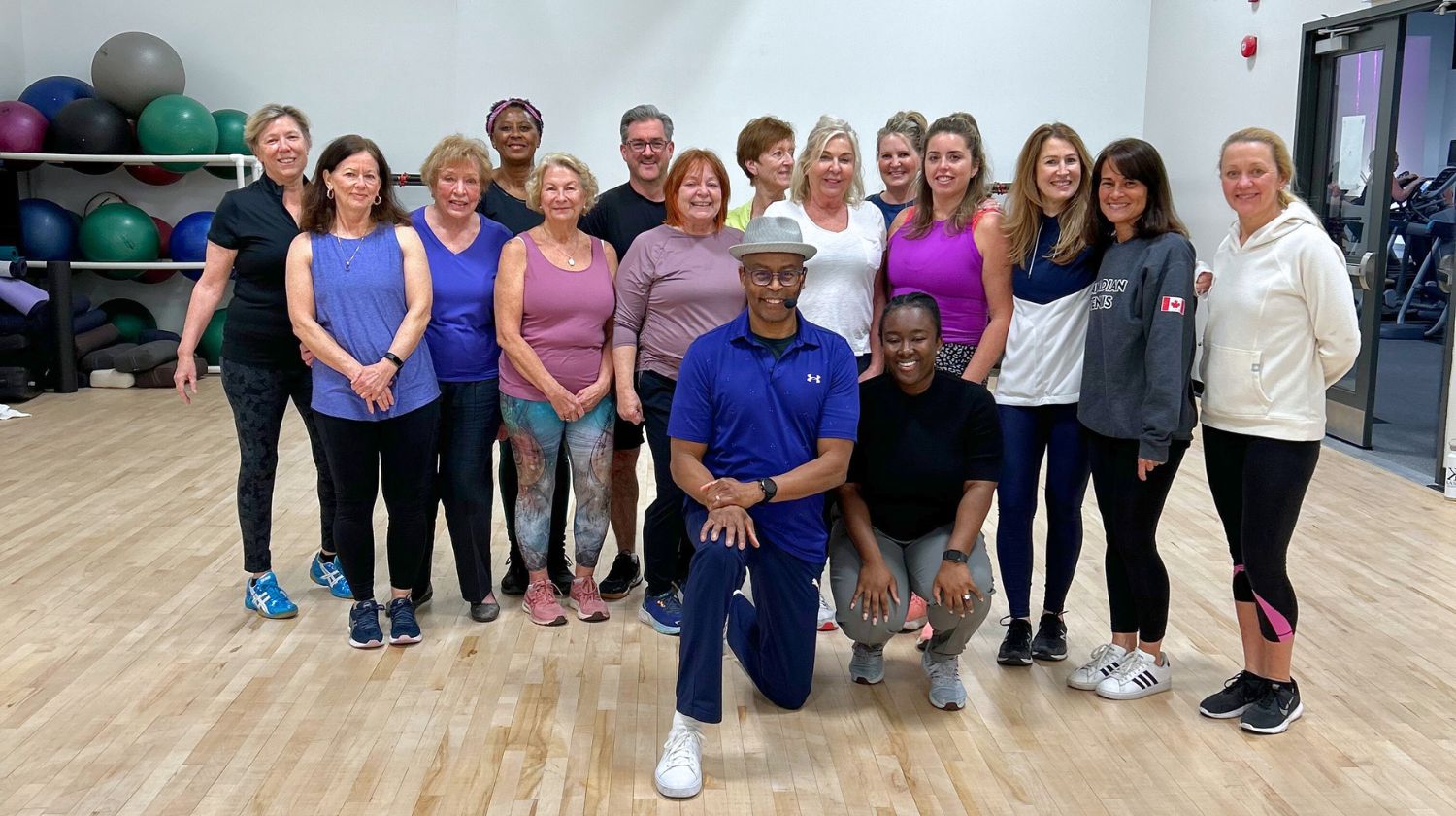 Image of group of group exercise participants smiling for a photo in the group exercise studio at our Mayfair Lakeshore Club.