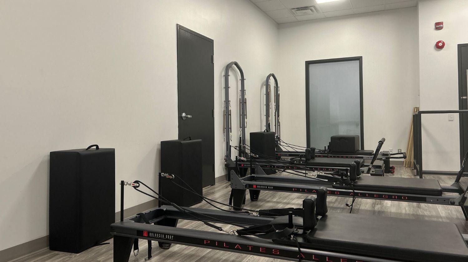 Image of our Pilates Reformer studio at our Mayfair Lakeshore location. There are three Pilates reformer machines in the image
