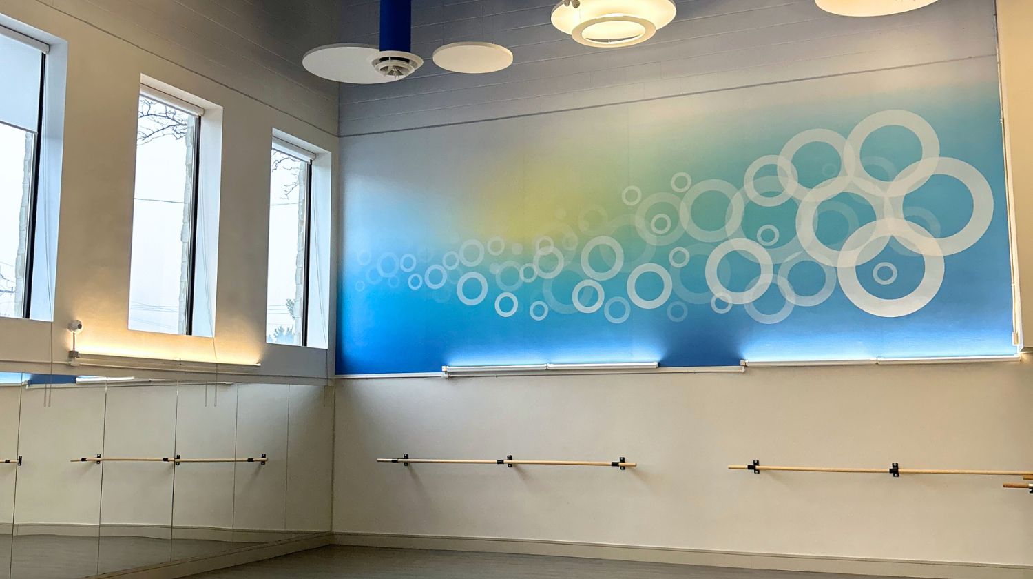 Image of the mind and body studio at our Mayfair West Club in North York. The room has a window and a blue mural with an illustration of circles on it.