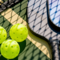 Photo of pickleball paddles and balls on a court.
