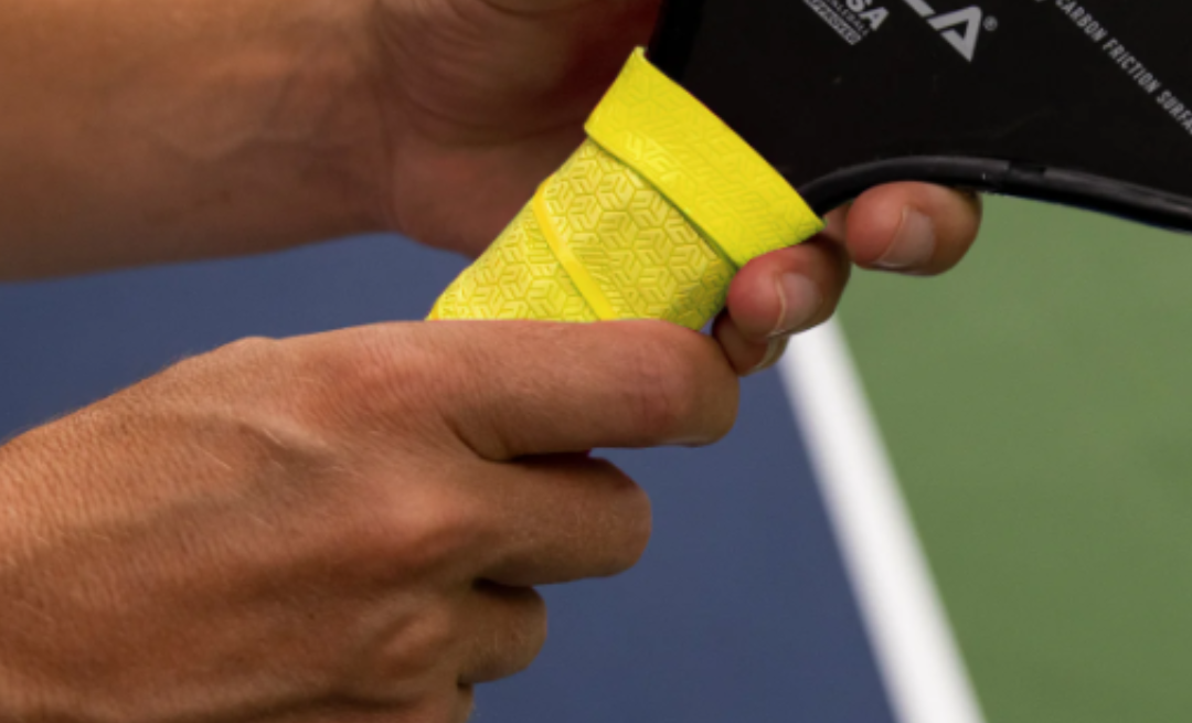 Image of person holding a pickleball paddle with Lizard Skin grips.