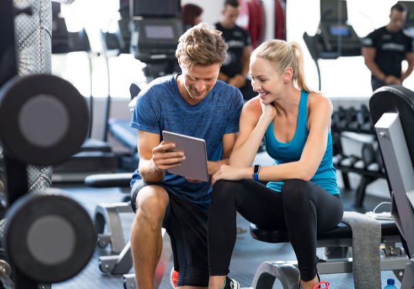 Male trainer working with female client in gym setting.