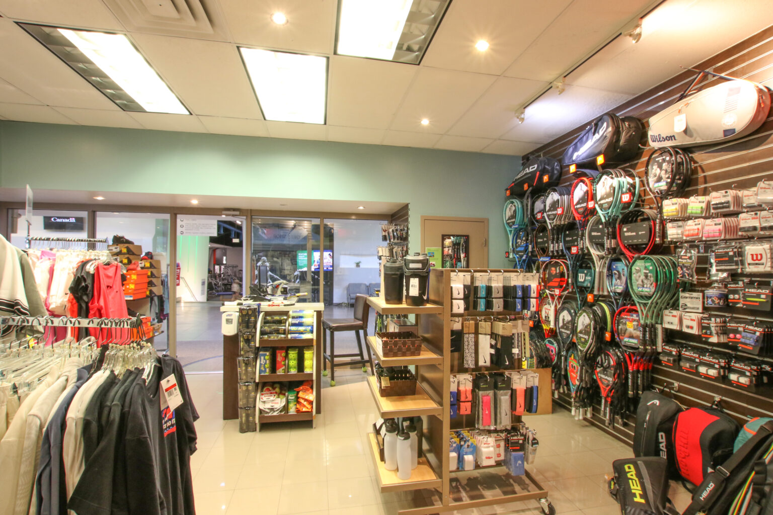 Image of wall of products - racquets bags, racquets for tennis and squash and other items in the Lakeshore Sports Shop.