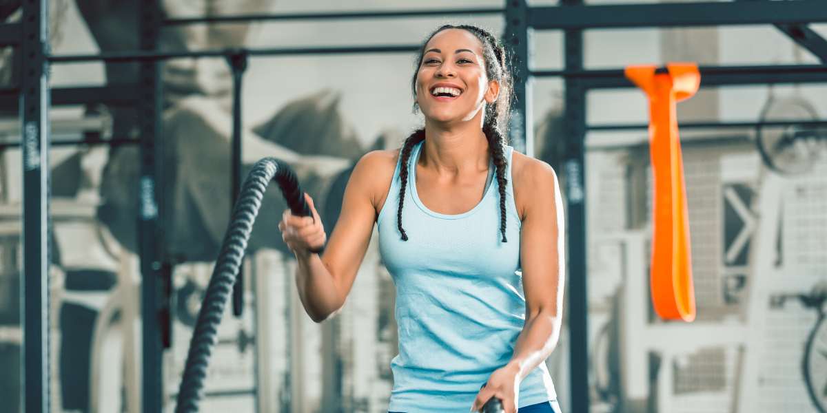 Young woman doing battle ropes in a gym.