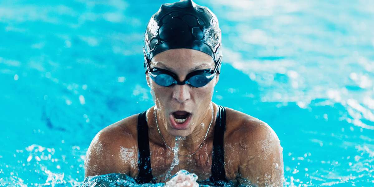 Woman swimming breast stroke in an indoor pool.