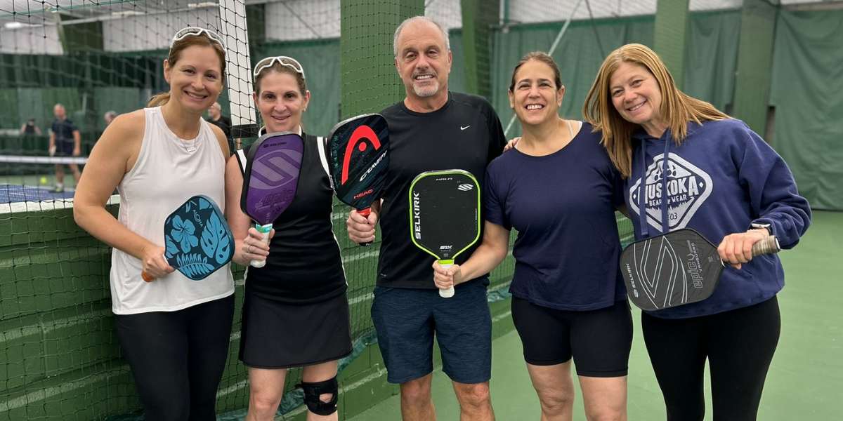 Group of middle aged people on a pickleball court with pickleball paddles.